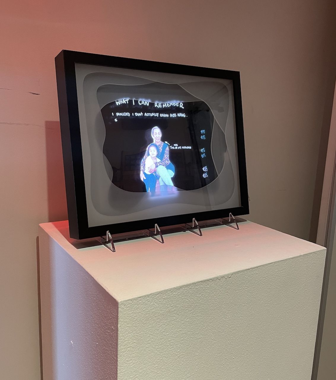 Photograph if a grandmother and child, in a black frame. Light-colored writing appears through the image.