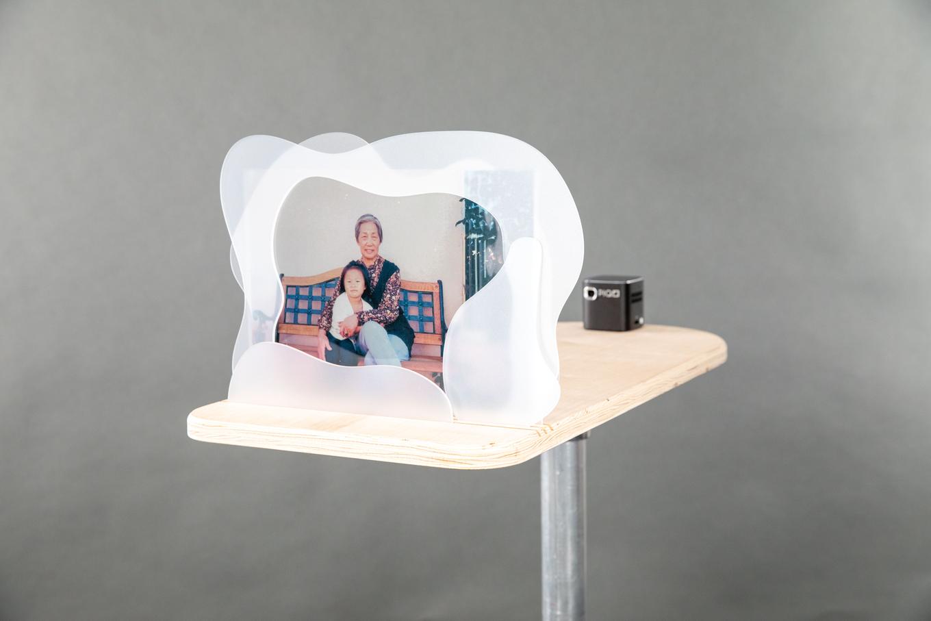 Image of a translucent photograph of grandmother and child, framed by organic acrylic shapes
